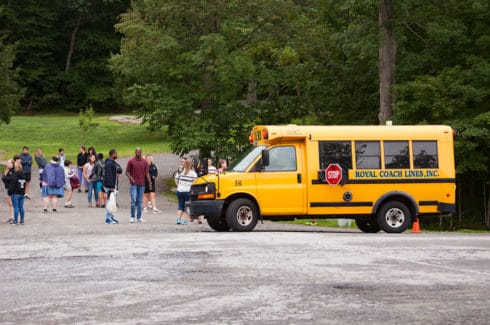 Yellow school bus dropping kids off at school.