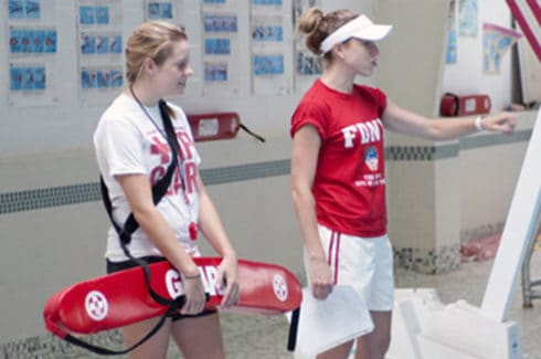 Two lifeguards standing at the side of the pool