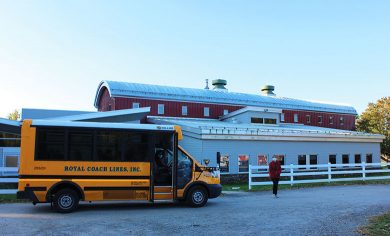 Images shows school bus in foreground with school building in the background.