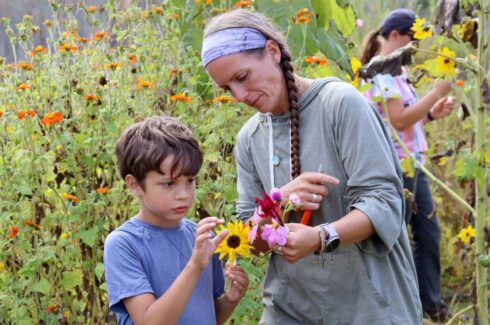 Green Chimneys garden teacher shows a young student a flower with a bumblebee pollinating.