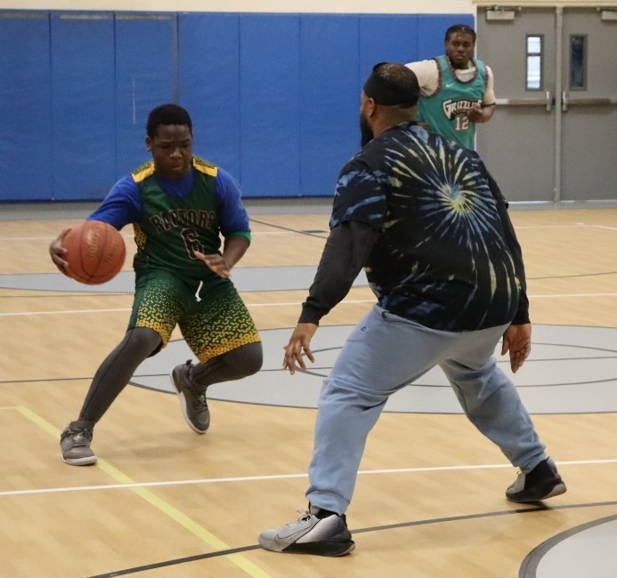 Green Chimneys student dribbles the basketball past Green Chimneys teacher Jordan Archible.