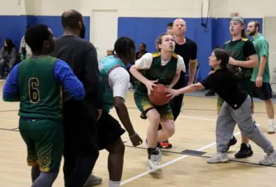 A group of people playing an indoor basketball game.